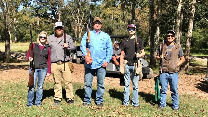 Group of people holding rifles outdoors.