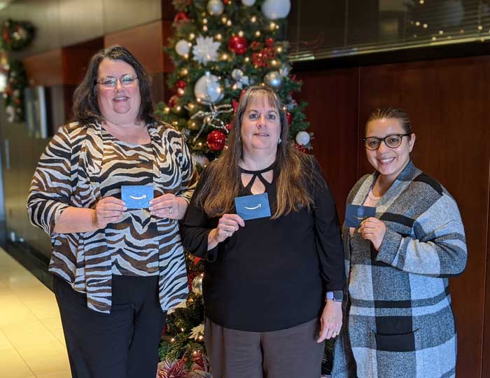 Three women holding gift cards.