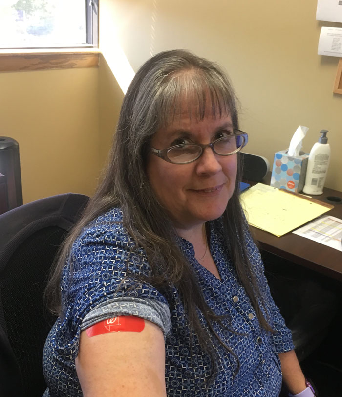 Person sitting with flu shot bandage.