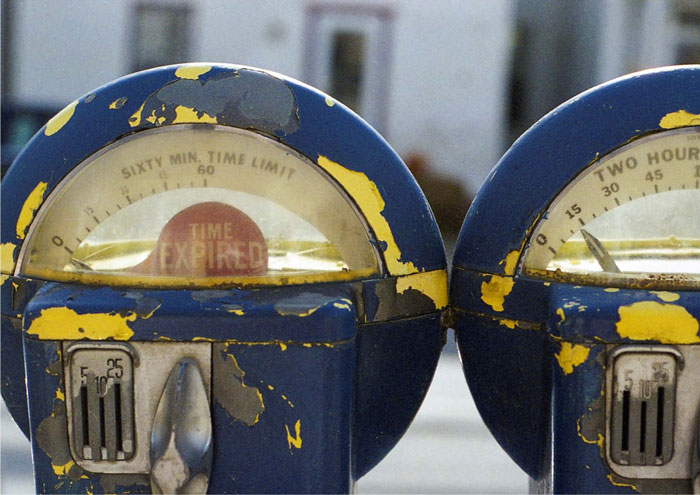 Two expired parking meters, peeling paint.