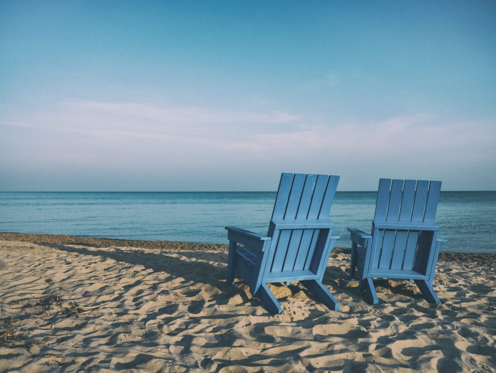 Two blue chairs on sandy beach