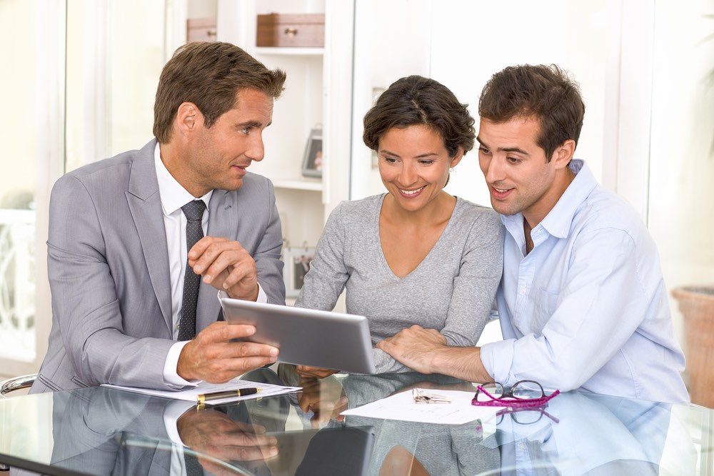 Three people discussing on a tablet.
