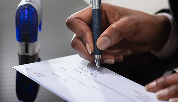 Hand signing a document with pen.