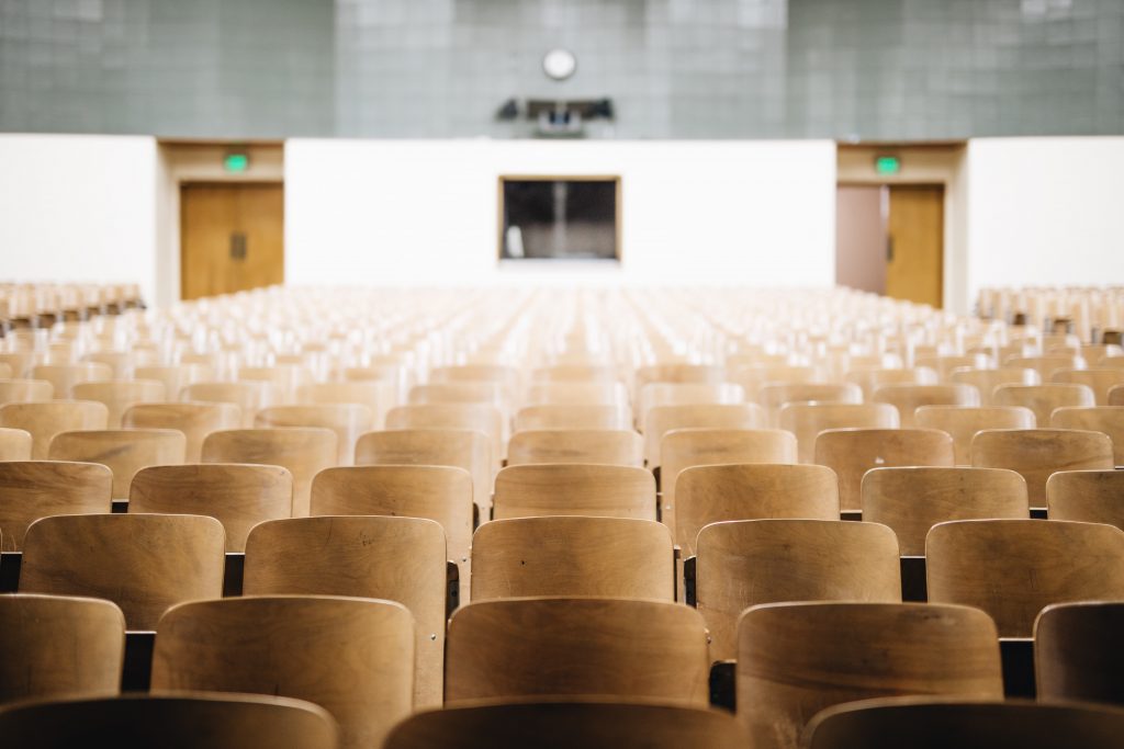 Empty auditorium with wooden chairs.