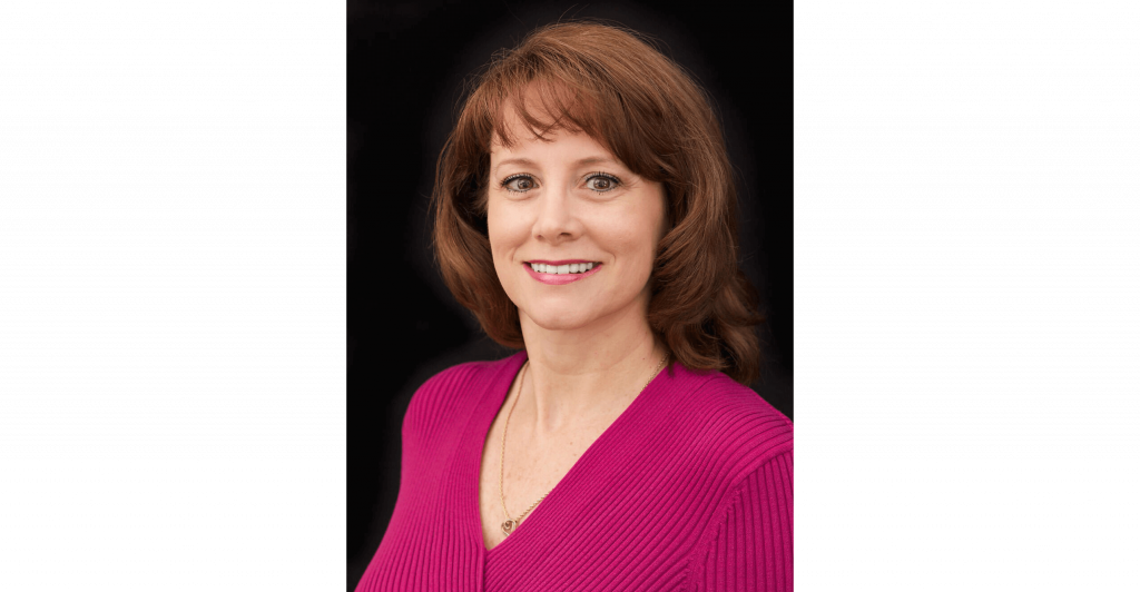 Woman in pink sweater, neutral background.