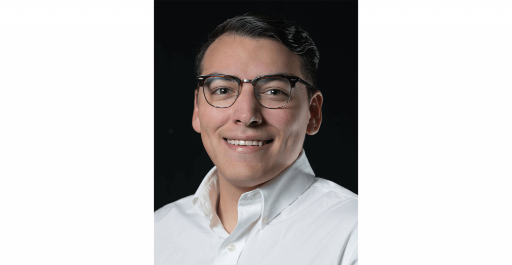 Person in white shirt, dark background.