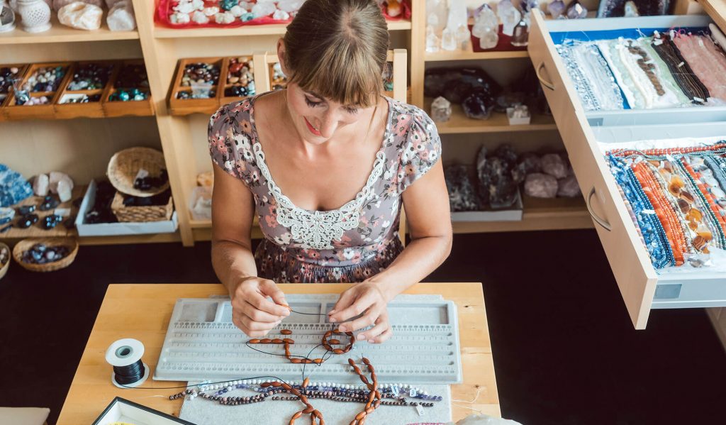 Woman crafting jewelry at a table.