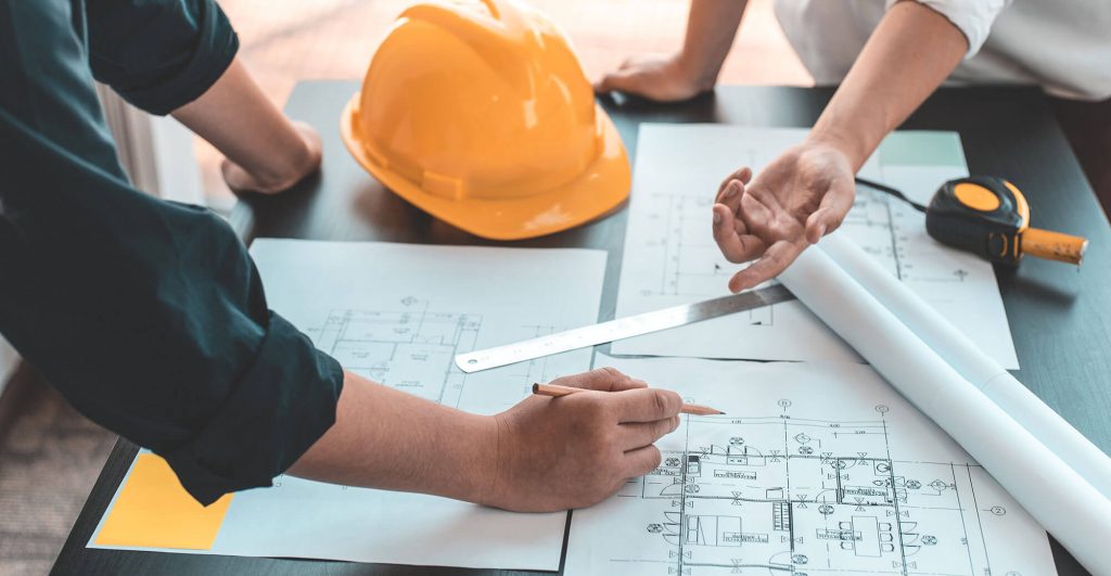 Hands discussing architectural blueprints and plans.