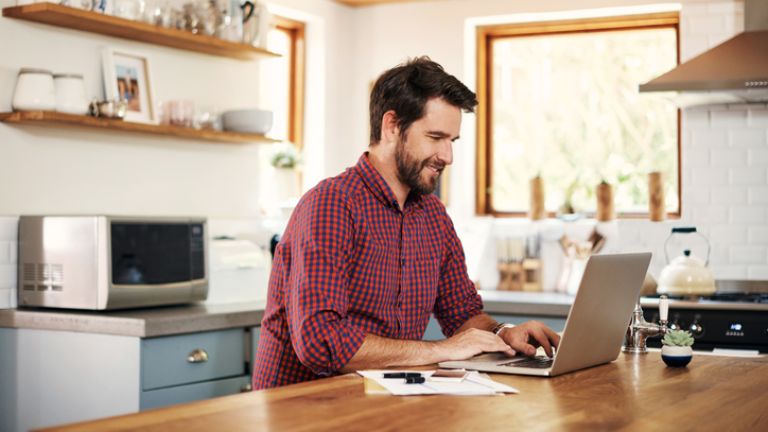 Person working on laptop in kitchen.