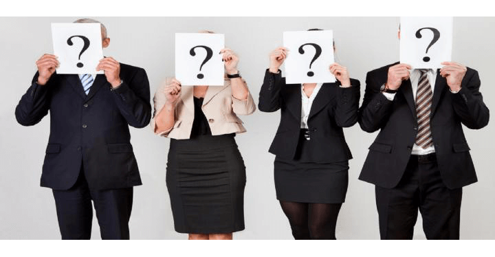 Four people holding question mark signs