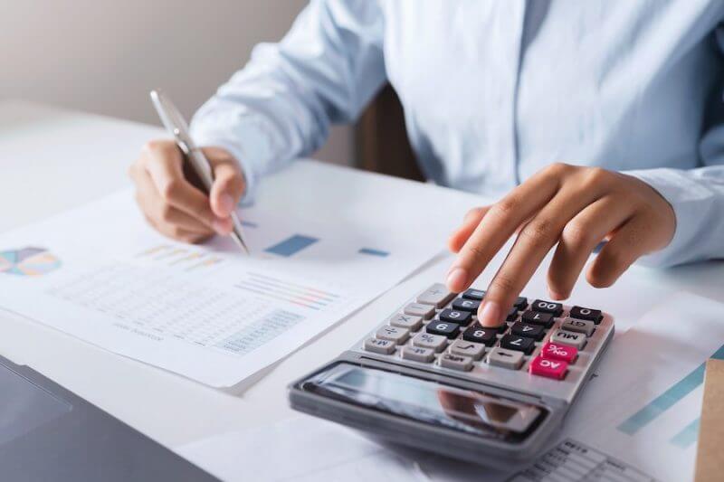 Person calculating financial data with calculator.