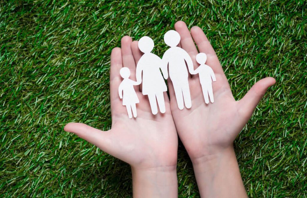 Hands holding paper family figures