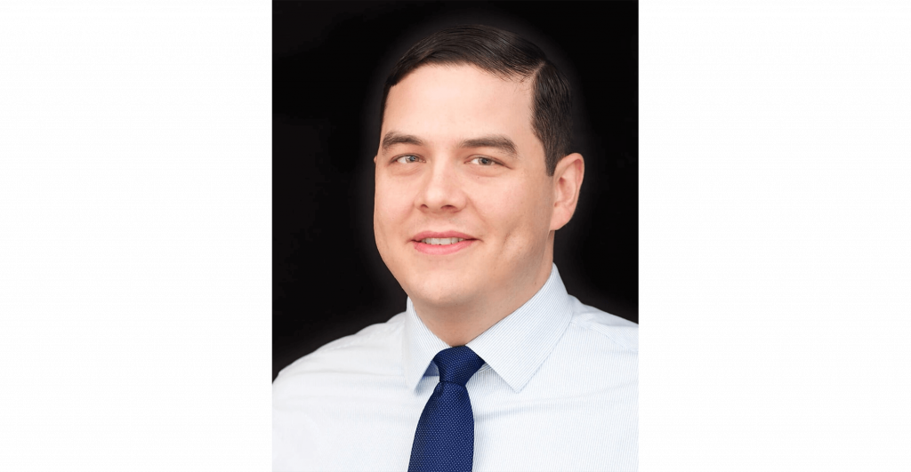 Man in formal attire, neutral background.