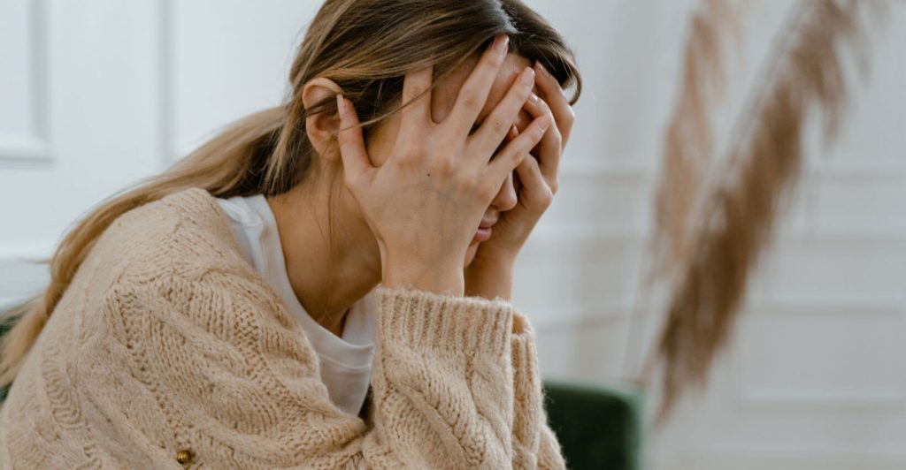 Person covering face with hand.