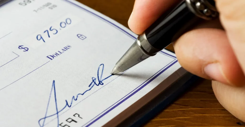 Hand signing a check for payment.