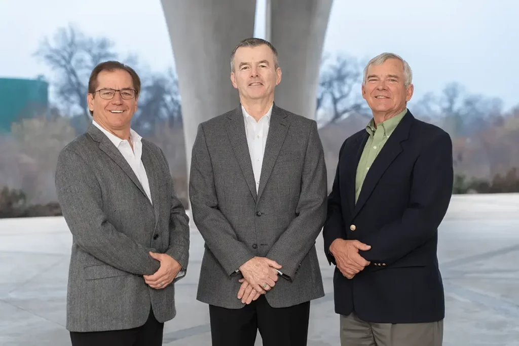 Three men standing under a structure.