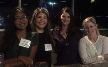 Four women posing together indoors.
