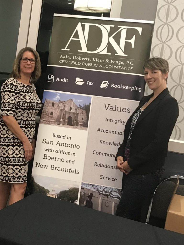Two women beside a company banner.