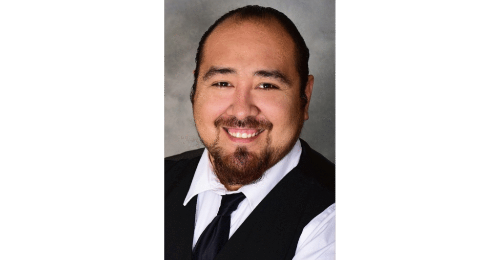 Man in formal attire, neutral background.