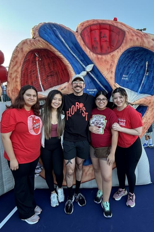 Group posing in front of heart sculpture.