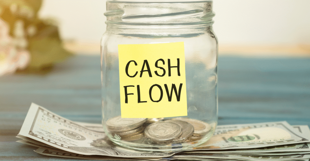 Glass jar with change in it on a table. Sticky note on jar that says cash flow